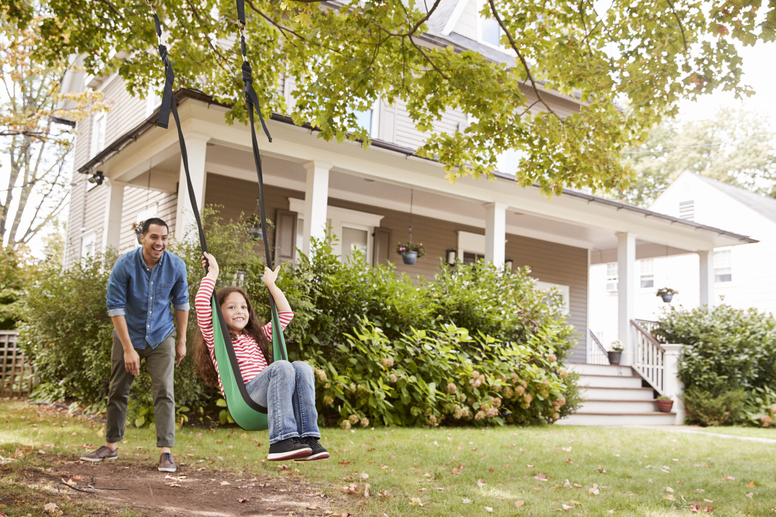 Father Pushing Daughter On Garden Swing At Home